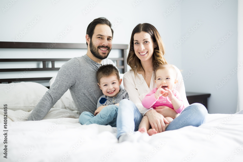 Wall mural four peoples family on a white bed.