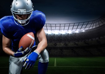American football player posing with rugby ball in stadium