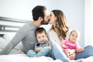 Obraz premium four peoples family on a white bed.