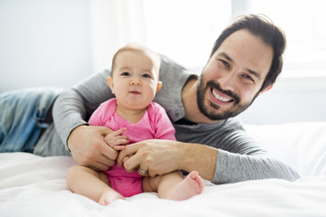 happy father playing with adorable baby in bedroom