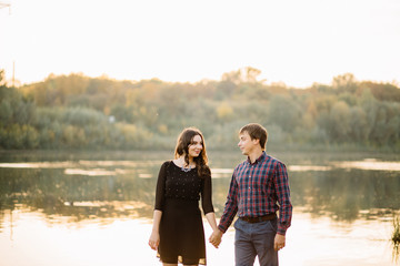 beautiful couple holding hands are facing each other in the eye near the great broad river, nature sun green trees