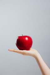 Woman on diet with an apple in the hand against gray background