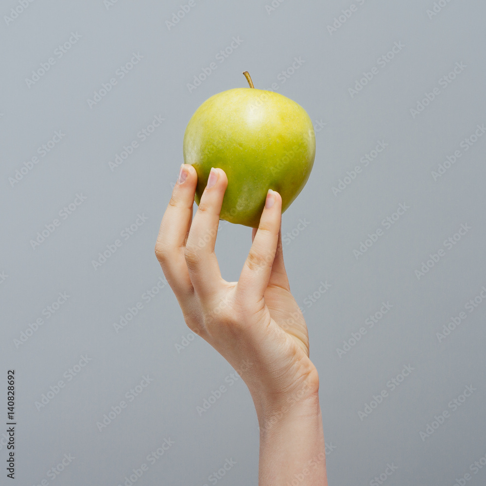 Wall mural Woman on diet with an apple in the hand against gray background