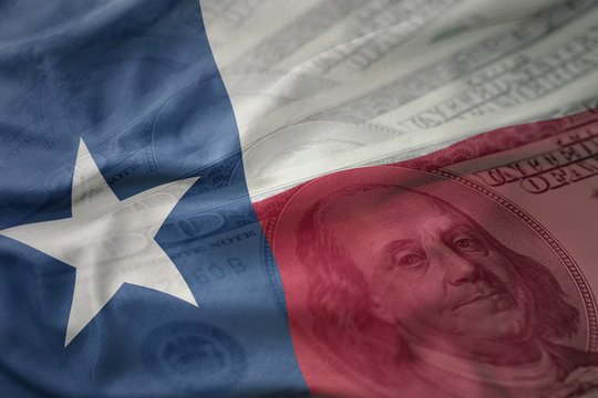 colorful waving flag of texas state on a american dollar money background. finance concept