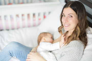 Young mother holding her baby child. Mom nursing baby.