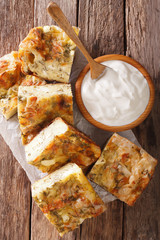 Traditional Serbian Gibanica with cheese, eggs and greens close-up and yogurt. Vertical top view