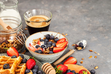 Breakfast table with cereal granola, milk, fresh berries, coffee and waffles