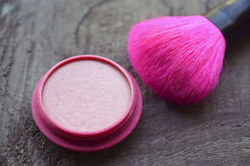 Pink makeup brush and blush on old wooden background with copy space.Fashion cosmetic make-up or woman beauty accessories concept.Selective soft focus.
