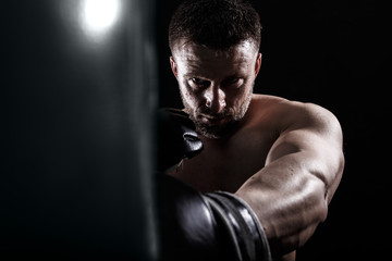 Fototapeta na wymiar Studio shot of male boxer punching a boxing bag.