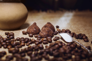 Coffee beans and chocolate candies on sackcloth close up. Coffee and sweets background.