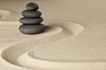 Fototapeta na wymiar Zen stone balance and harmony, a pile of dark black stones stacked in a Japanese sand garden.