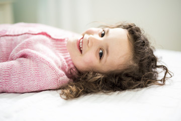 Happy child in the bed wearing in pink