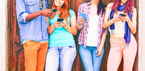 Group of teenagers texting  mobile phone messages leaning against urban  wall - Row of best student...