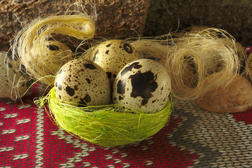 quail egg, three in a nest of dry grass and fiber on ornament