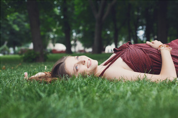 Beautiful young girl lying on grass in summer park