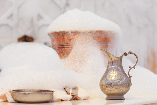 Water jar, towel and copper bowl with soap foam in turkish hamam. Traditional interior details