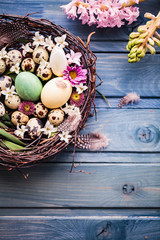 Obraz na płótnie Canvas Nest with easter eggs on a blue wooden background