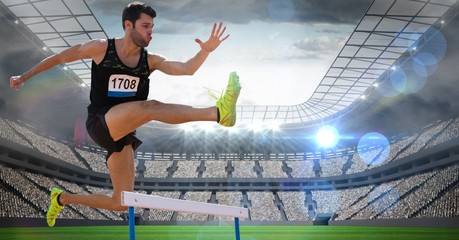 Fototapeta na wymiar Male athlete jumping above the hurdle in stadium
