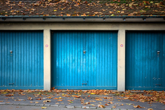 Drei blaue alte Garagen mit Schwingtor - Garagentore im Herbst mit Laub