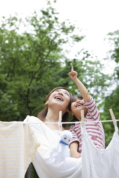 Mother and daughter standing behind clothesline and holding teru teru bozu