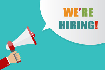 Obraz premium Hand holding Megaphone with speech bubble on blue background with words we're hiring, vector illustration