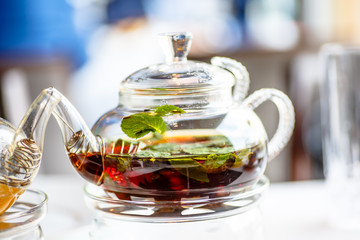 Tea with mint leaves in a glass teapot with a candle.