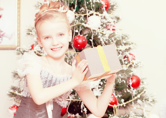 The little girl at the Christmas tree enjoys the gifts.