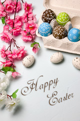 Painted easter eggs and branches of spring sakura closeup on a light blue background with space for congratulation