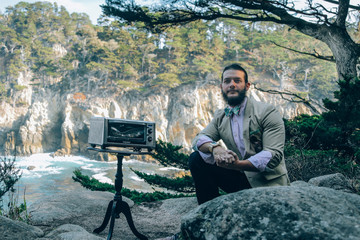 Fototapeta premium Man sitting with Microwave on California Coastline