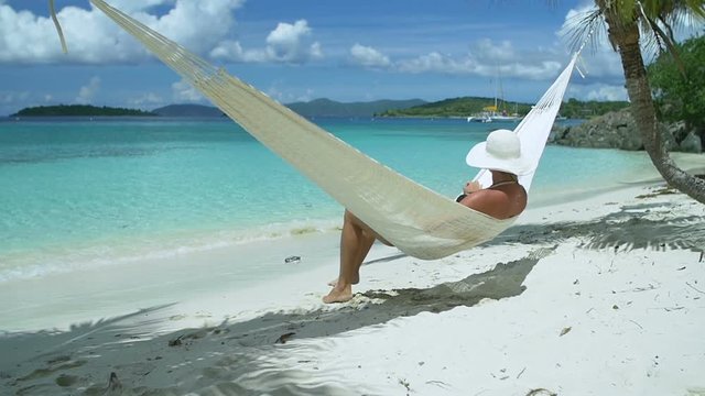 slow motion video of a woman relaxing in hammock on perfect tropical beach