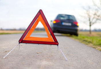 breakdown triangle stands near a broken car