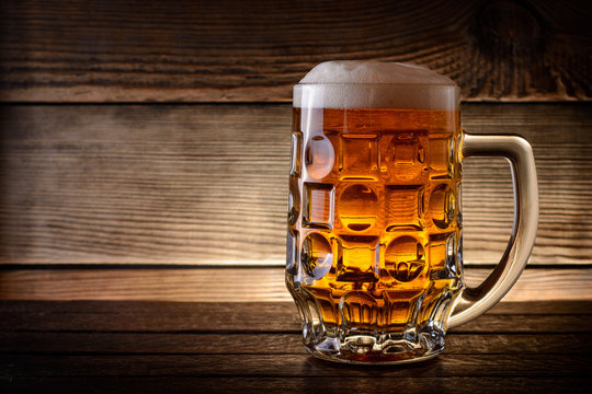 Mug of beer on rustic wooden background with copy space.