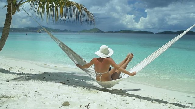 slow motion video of a woman relaxing in hammock on perfect tropical beach