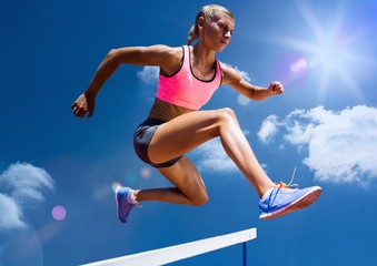 Fototapeta na wymiar Female athlete jumping above the hurdle