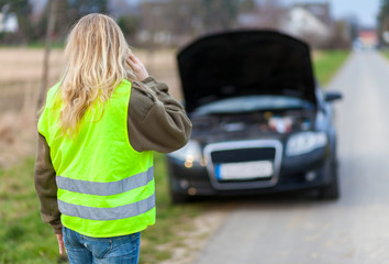 a woman with reflective vest stands on a broken car