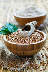 Scoop with buckwheat flour in a bowl with buckwheat.