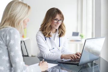 Doctor and her patient. Shot of a middle aged female doctor sitting in front of laptop and...