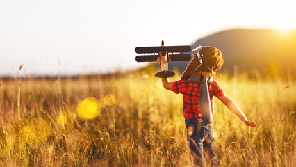 Child pilot aviator with airplane dreams of traveling in summer  at sunset