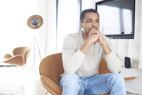 Enjoy my life. Shot of an African American young man relaxing at home on the sofa while looking at camera and smiling.