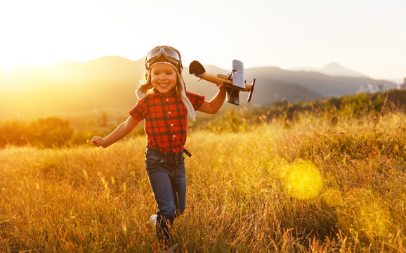 Child pilot aviator with airplane dreams of traveling in summer  at sunset.