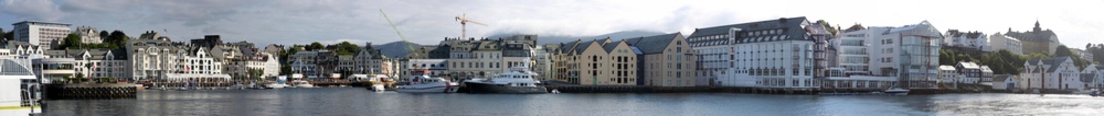 Fototapeta premium Panorama am Hafen der Stadt Alesund, Norwegen, mit Leuchtturm, alten Lagerhäusern und Hotels an der Hafenmole