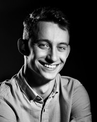 Close-up of young smiling man resting chin on palm looking upwards, black and white