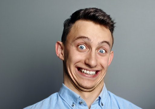 A man laughing hysterically at something hilarious with a funny expression on his face.