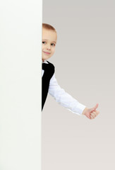 boy peeks out from behind the banner