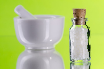 Kleine Flasche mit Globuli und Mörser