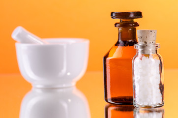 Kleine Flasche mit Globuli und Mörser