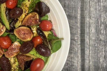 Fresh salad in bowl on wood surface