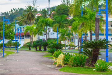 Fototapeta na wymiar empty footpath with Golden bench in the Park. The green quay road in Samana, Dominican Republic