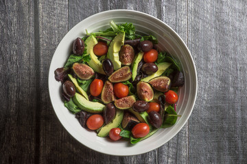Fresh salad in white bowl on wood