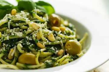 Fresh and tasty Italian Pasta with green spinach, green olives, pine nuts and cheese, Horizontal.